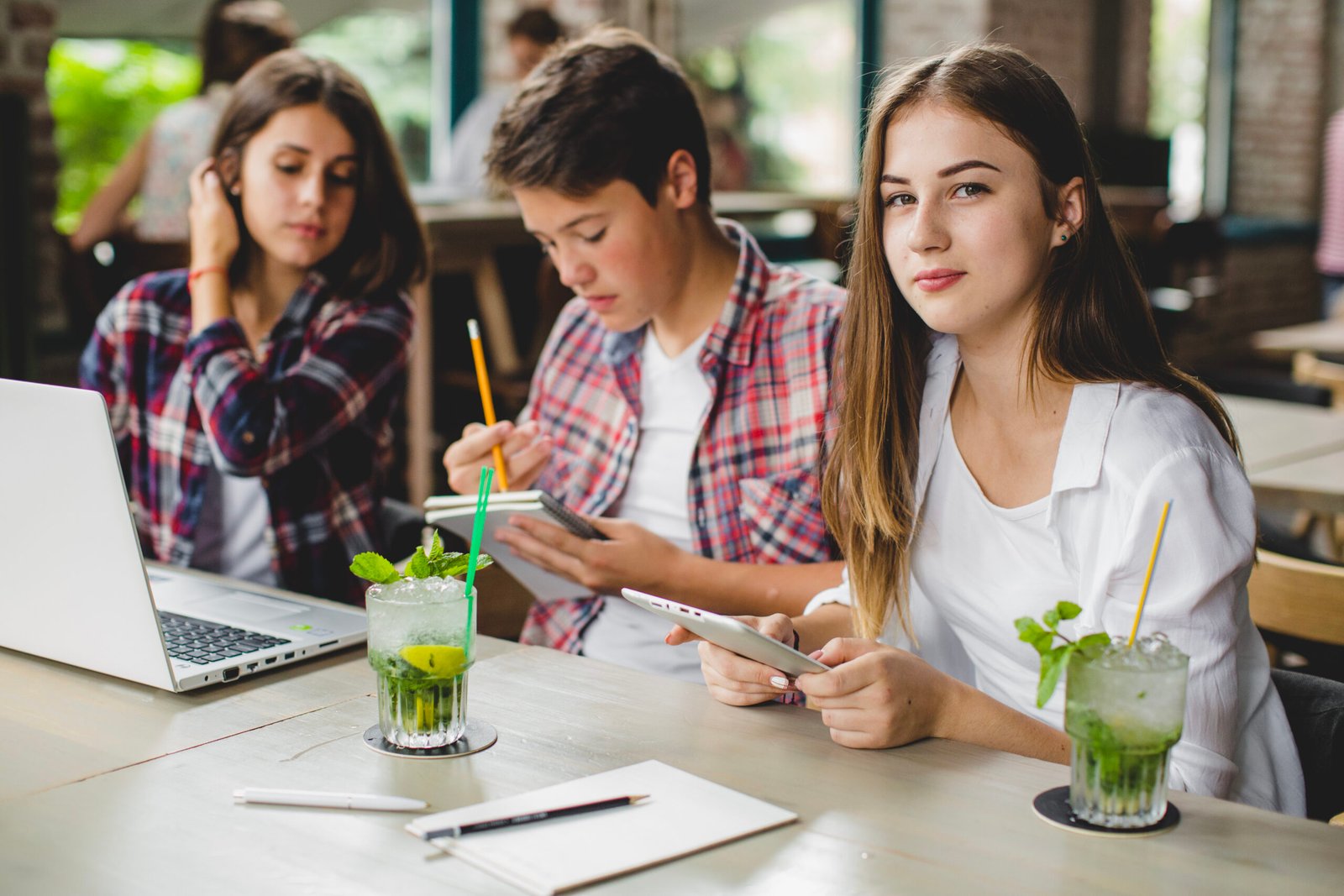 three students with gadgets cafe